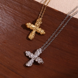 Close-up of hammered gold and silver cross pendants on a dark wooden background