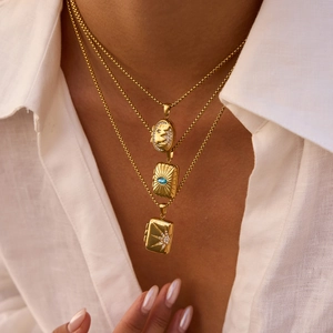 Detailed view of triple-layered gold sun and star locket necklaces worn by a model