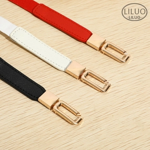 Detailed close-up of slim elastic belts in red, white, and black with gold metal buckles