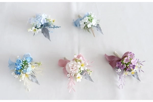 Detail of five artificial wedding boutonniere corsages in pastel colors with silk ribbons