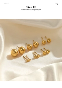 Detail view of multi-size gold ball stud earrings arranged on white silk fabric