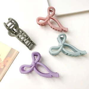 Matte bow hair clips in pink, light blue, purple, and grey-green on a white surface