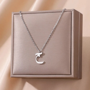 Detail of silver Arabic letter pendant necklace on champagne satin jewelry box