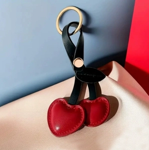 Pastoral cherry leather keychain with red heart fruits and golden ring on pink silk