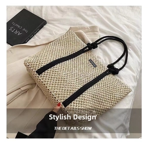 Close-up of woven straw tote bag with black rope handles and hollow texture detail