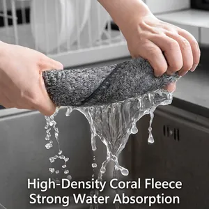 Absorbent charcoal fiber kitchen cloth being wrung out by hand to show high water drainage