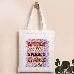 Detail of white canvas tote bag with Spooky Vibes Halloween pumpkin and skull print