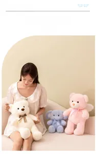 Close-up of soft plush pink angel bear and blue elephant toys held by a model
