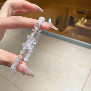 Detail of beaded bracelet with translucent white stones and a clear butterfly pendant