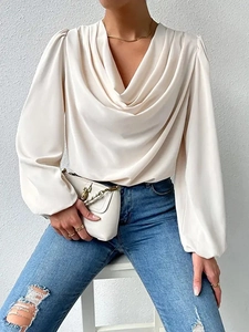 Detail of elegant cream chiffon blouse featuring a draped V-neckline and soft textures