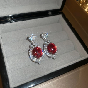 Macro shot of oval red gemstone earrings with white crystal halo in a jewelry box