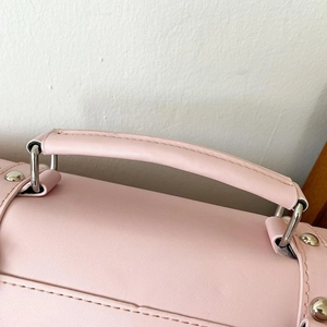 Detail of pink faux leather handbag handle with silver hardware and crossgrain texture