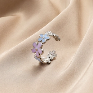 Close-up of adjustable flower ring with purple and blue enamel on beige silk
