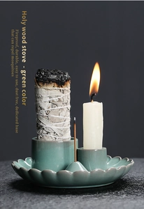 Macro shot of green ceramic holy wood stove with white sage, incense and candle setup
