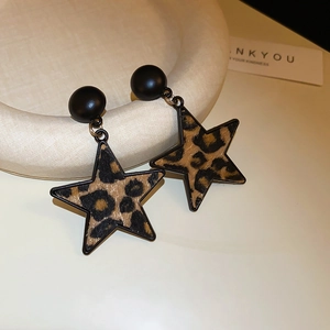 Close-up of leopard print star drop earrings with black beads on a beige prop