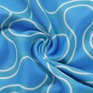 Close-up of blue swimsuit fabric featuring white wave patterns and a soft texture