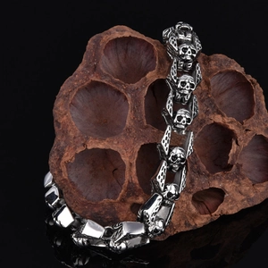 Detailed close-up of a stainless steel skull and crossbones link bracelet on lotus pod