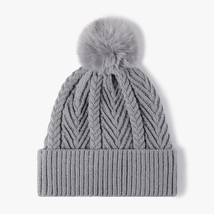 Grey cable knit beanie hat with a fluffy faux fur pompom and ribbed cuff for women