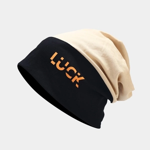 Detail of knit beanie with orange LUCK lettering and black-beige color block