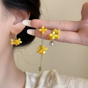 Detailed view of osmanthus pearl earrings featuring yellow petals and green crystal tassels