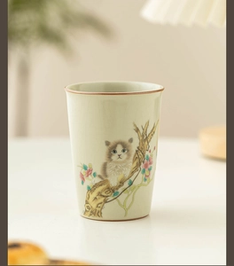 Detail of Ru Kiln beige ceramic tea cup with a cute cat painted on a tree branch