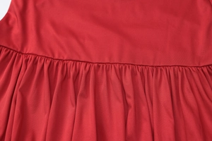 Detailed view of red pleated fabric with professional stitching on a V-neck dress