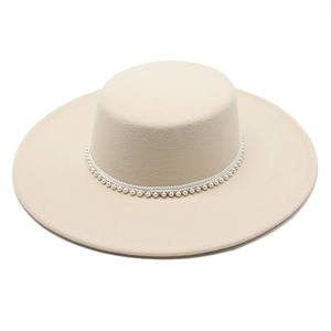 Dettaglio del cappello in lana beige con decorazioni di perle e bordo in pizzo bianco
