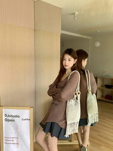 Detail of hand-woven tassel tote bag with wooden handles styled with casual chic outfit