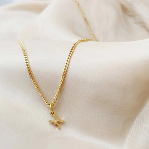 Close-up macro view of golden titanium steel Pisces zodiac pendant on elegant cream fabric