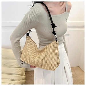 Detail of woven straw tote bag texture with slim black leather shoulder strap