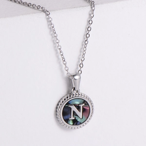 Macro view of silver stainless steel pendant with letter N and mother of pearl inlay