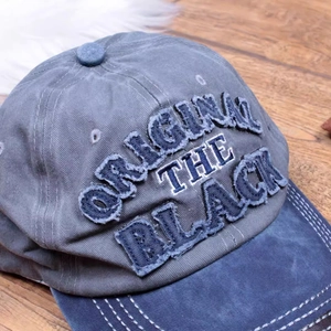 Close-up of vintage grey-blue washed cotton baseball cap with 3D letter embroidery