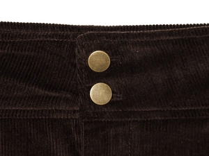 Detailed macro view of dark brown corduroy fabric featuring two vintage bronze buttons