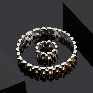 Close-up of two-tone stainless steel bracelet and ring set on black reflective surface