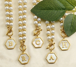 Détail de colliers en acier inoxydable avec boucle OT et pendentifs lettres en nacre