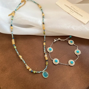Flat lay of beaded stone necklace with blue oval pendant and turquoise silver bracelet