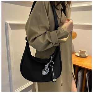 Detail view of black oxford half-moon crossbody bag with daisy strap and shoe charm