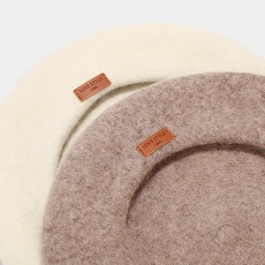 Detailed texture of wool beret with leather label showing LOVE STYLE 1988 engraving