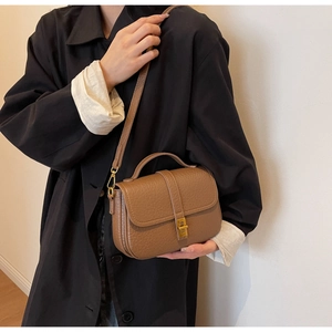 Close-up of vintage brown textured leather handbag with gold buckle and adjustable strap