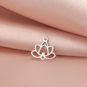 Detail view of silver stainless steel lotus charm on soft pink silk background