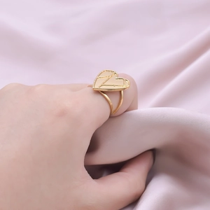 Detail of a gold-tone geometric heart ring with hollow lines and double-wire band
