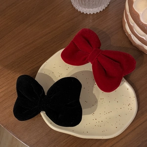 Velvet bow hair clips in red and black colors for girls displayed on a ceramic tray