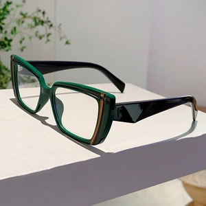 Detail view of stylish green and black cat-eye glasses frame on a minimalist pedestal