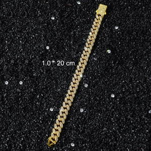 Detailed view of 10mm gold Cuban link bracelet with iced-out rhinestones on black sand