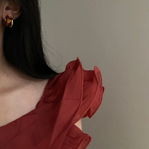 Detail view of retro amber resin C-shaped earrings paired with deep red ruffle clothing