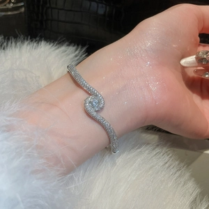 Macro shot of 18k gold plated S-shape bangle with cubic zirconia on female wrist