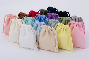 Colorful assortment of drawstring cotton bags in white, yellow, pink, and purple tones