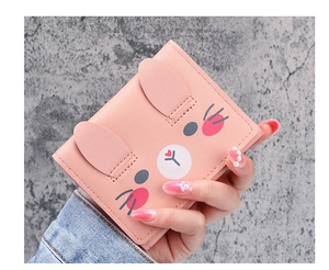 Close-up of cute pink cartoon rabbit wallet in model's hand against grey background