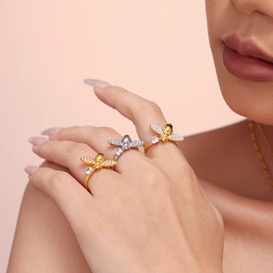 Gold and silver bee rings with white zircon stones worn on fingers in a lifestyle setting