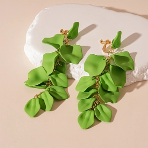 Detail showing long green acrylic petal earrings with gold chain on a stone display